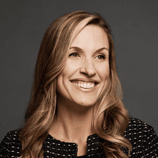 Professional headshot of Emily Couey, smiling with long blonde hair and wearing a black patterned top.