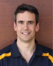 Portrait of Dr. Albert Solé Guitart in a dark polo shirt with yellow accents standing in front of a reddish-brown background.
