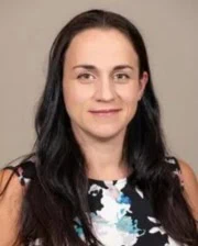 Portrait of veterinarian Carina Cooper wearing a sleeveless floral top against a neutral background.