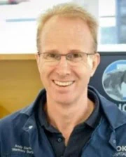 Portrait of Dr. Andy Durham smiling and wearing a navy veterinary uniform with glasses.
