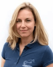 Dr. Emmanuelle van Erck smiling, with blonde hair, wearing a navy polo shirt with an equine logo.