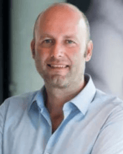 Dr. Filip Vandenbergher smiling, wearing a light blue collared shirt, with arms crossed.