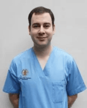 Dr. Gabriel Manso Diaz wearing light blue medical scrubs, standing against a plain background.