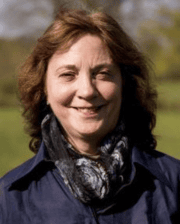 Dr. Virginia Reef smiling outdoors, wearing a navy jacket and patterned scarf.
