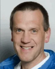 Professional headshot of Dr. Hubert Simhofer wearing a blue jacket and white shirt, smiling against a neutral background.