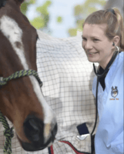 Dr. Kirsten Jackson smiling while examining a horse with a stethoscope.