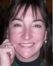 Portrait of Dr. Lynn Caldwell smiling, wearing earrings and a dark top.