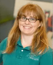 Dr. Molly Rice smiling while wearing glasses and a green embroidered polo shirt.