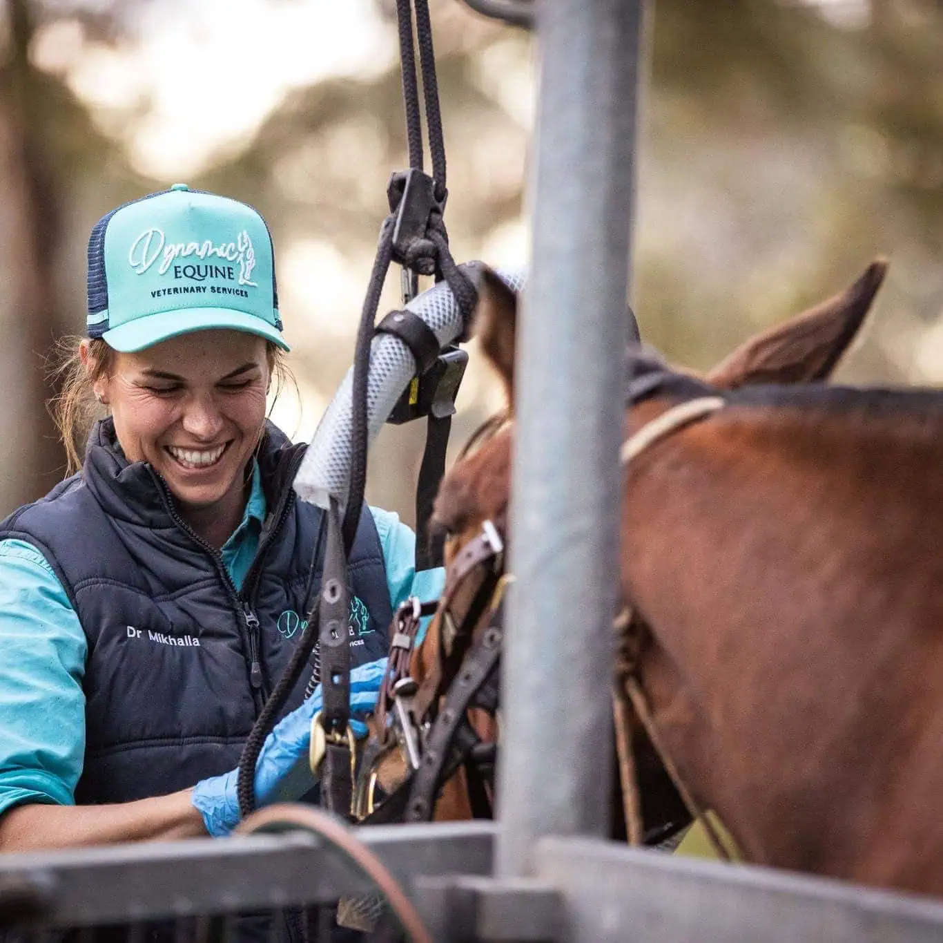 Dr. Mikhalla Middleton smiling while performing an equine dental procedure using specialized equipment.