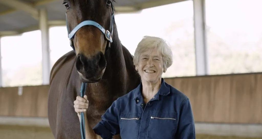 close up image of dr sue dyson smiling with a brown horse