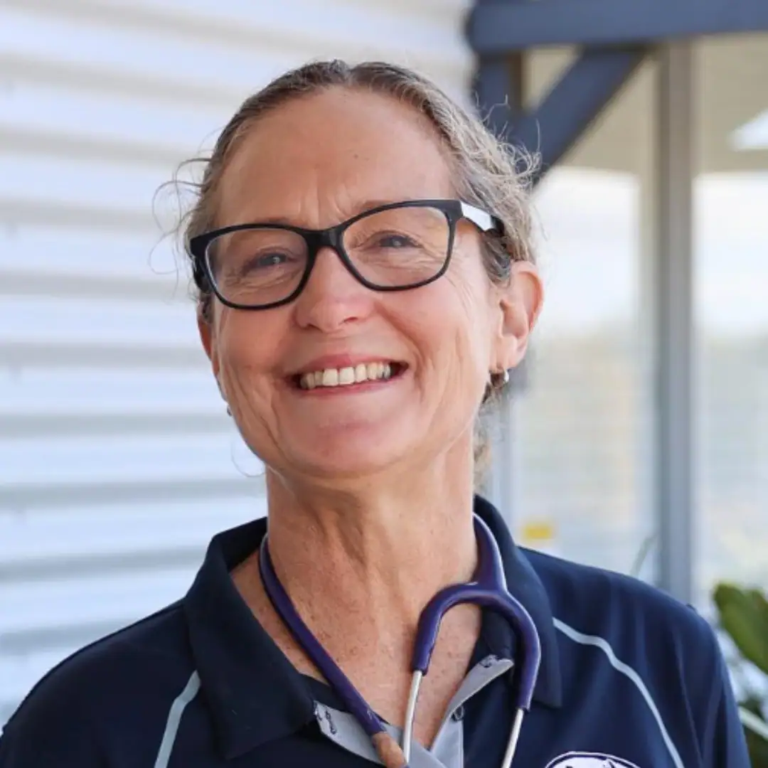Dr. Shaan Mocke smiling while wearing a stethoscope and navy veterinary uniform outside a clinic.