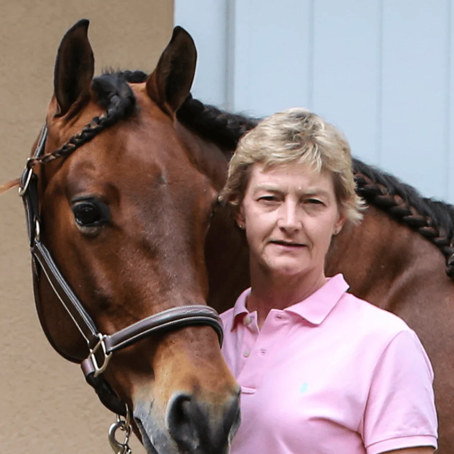 Equine lameness specialist standing beside a horse in a professional portrait highlighting expertise in equine performance and diagnostic medicine